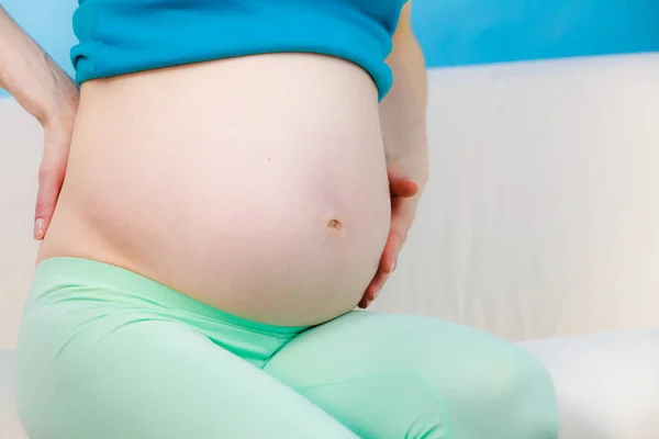 妊娠中の女性は 彼女の背中に手で自宅でソファに座って マッサージを作り 痛みに苦しんでいます 健康の概念 — ストック写真