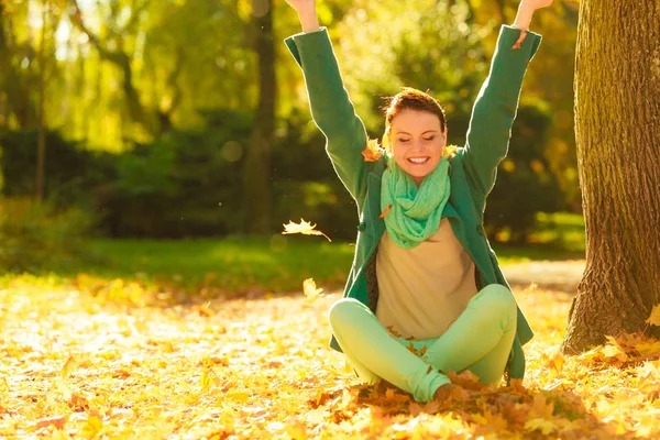 幸福的女人扔秋季叶片在公园期间美丽晴朗的秋天天气 — 图库照片