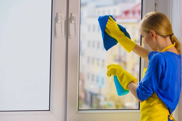 ラグとスプレー洗剤で自宅で黄色の手袋のクリーニングウィンドウペインの若い女性 清掃コンセプト — ストック写真