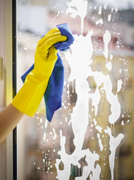 ラグとスプレー洗剤で黄色の手袋のクリーニングウィンドウペインの女性の手 清掃コンセプト — ストック写真