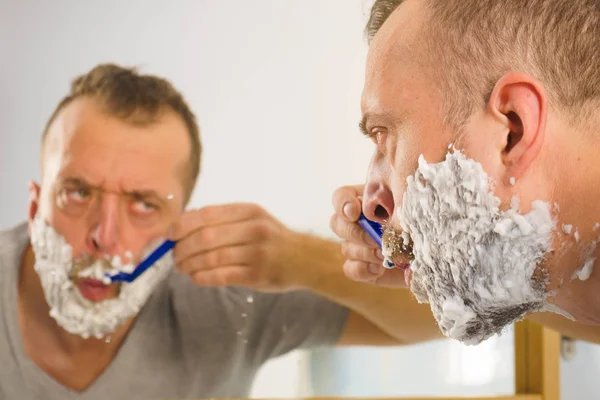 Mann Mit Viel Rasierschaum Gesicht Steht Badezimmer Schaut Den Spiegel — Stockfoto