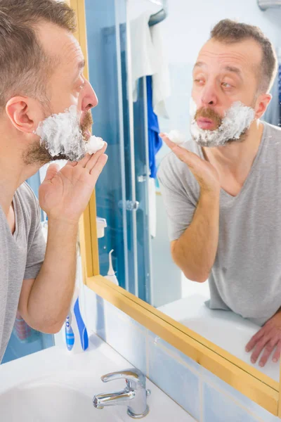Muž Nanáší Pěnový Krém Obličej Stojí Koupelně Dívá Zrcadla Připravuje — Stock fotografie