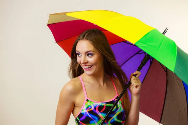 Lycklig kvinna poserar i baddräkt och färgglada paraply — Stockfoto