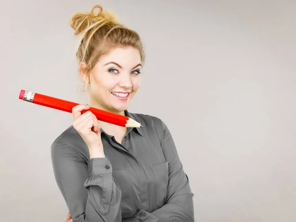 Smiling woman holds big pencil in hand — Stock Photo, Image