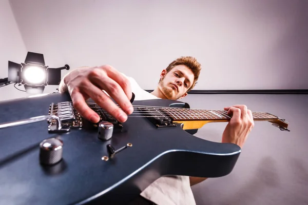 Jovem está tocando guitarra elétrica — Fotografia de Stock