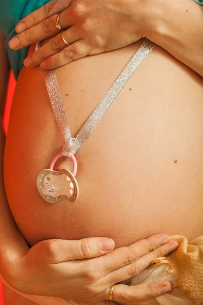 为人父母 等待宝宝的概念 显示她怀孕大肚子控股奶嘴的成年女性 红色背景室内拍摄 — 图库照片