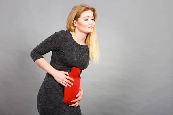強い胃の痛みを持っている女性 女性は腹部に赤い湯たんぽを保持している腹の痛みに苦しみます 痛みの概念の医療 — ストック写真