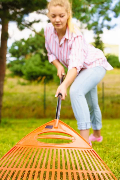 女青年在自家后院用耙工具耙绿色草坪草 视角广袤异常 — 图库照片