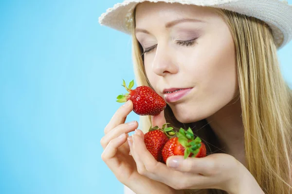 年轻的妇女闭上眼睛闻到新鲜的草莓水果在蓝色 健康膳食 — 图库照片