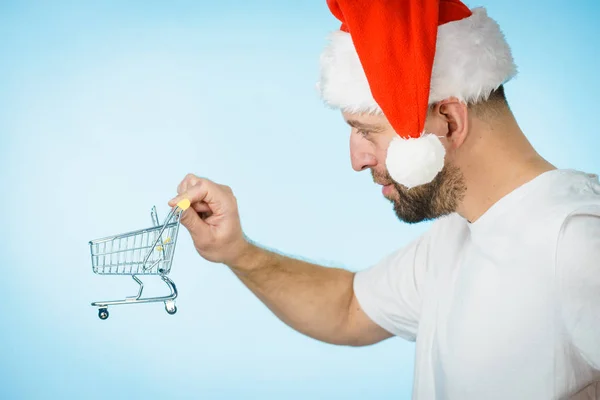 Mann Mit Weihnachtsmann Mütze Und Leerem Einkaufswagen Auf Blauem Grund — Stockfoto