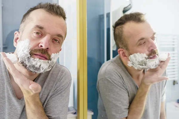 Hombre Aplicando Crema Espuma Afeitar Cara Pie Baño Mirando Espejo —  Fotos de Stock