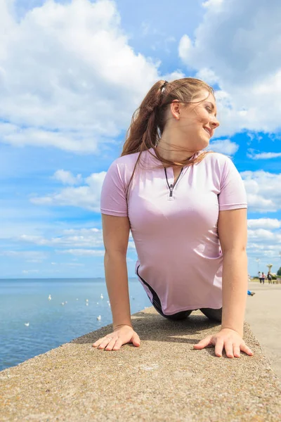 晴れた日には外で活躍するファッショナブルな衣装を着た魅力的な若い女性にスーパーフィット ストレッチ彼女の背中や練習ヨガ海の横に — ストック写真