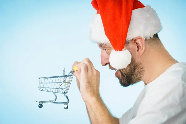 Mann Mit Weihnachtsmann Mütze Und Leerem Einkaufswagen Auf Blauem Grund — Stockfoto