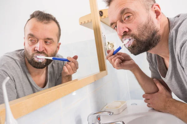 Volwassen Man Poetsen Zijn Tanden Kijken Naar Zijn Badkamer Spiegel — Stockfoto