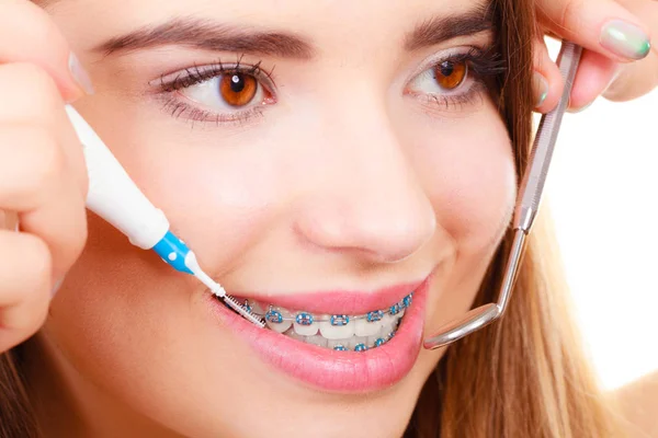 牙科医生和牙医的概念 年轻女子微笑的清洗和戴着蓝色牙套使用牙刷和镜子刷牙 — 图库照片