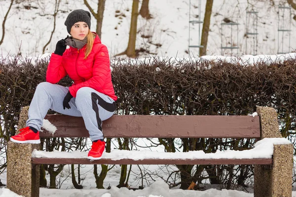 户外运动锻炼 运动的装备想法 冬季户外坐在长凳上穿暖和运动休闲的妇女 — 图库照片