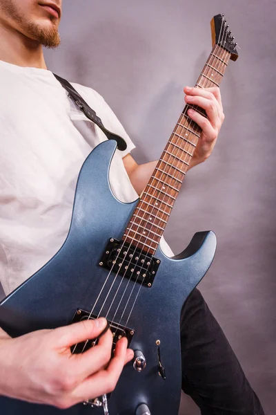 Close up of man playing on electric guitar during gig or at music studio. Musical instruments, passion and hobby concept.