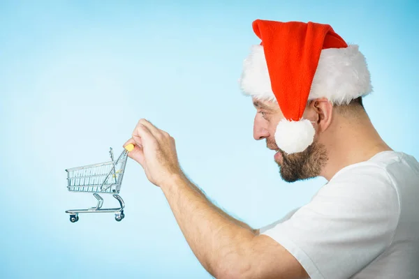 头戴圣诞礼帽的男人拿着空购物篮推车 蓝色的 圣诞节 季节性销售 拳击日的概念 — 图库照片
