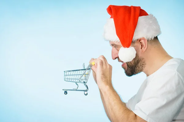 Mann Mit Weihnachtsmann Mütze Und Leerem Einkaufswagen Auf Blauem Grund — Stockfoto