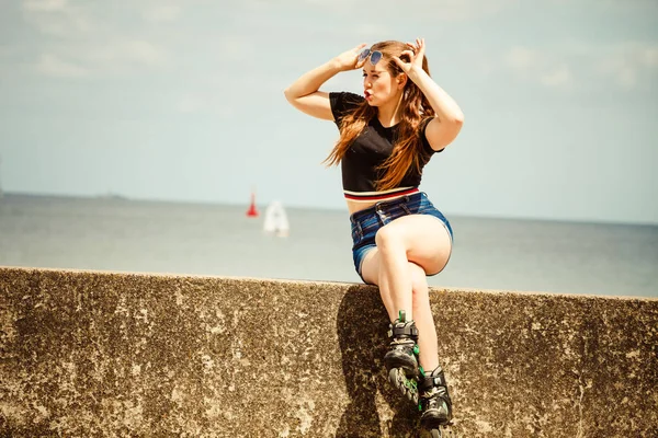 長い乗車後にリラックスローラースケートを身に着けている幸せな若い女性 女性は海の近くで夏の時間の間にスポーツを楽しんでいる — ストック写真