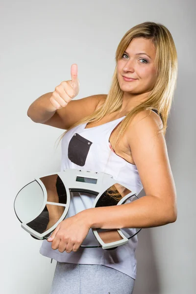 ダイエット フィットネス スリミング 失う重量制 ジェスチャを計量機表示の親指を保持している幸せな金髪女 — ストック写真