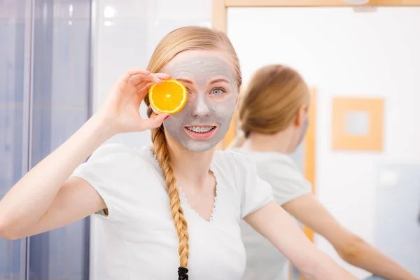 顔の乾燥した皮膚やボディケア 自宅の概念での肌の治療 幸せな若いです女性持っています灰色泥マスクオン彼女の顔保持オレンジ色の作品 — ストック写真