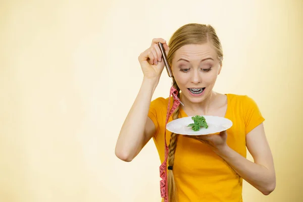 ショックを受けた若いのブロンドの女性は神経性無食欲症や Builimia プレートの小さな緑の野菜を持っていることを扱います ダイエット 摂食障害の問題 — ストック写真