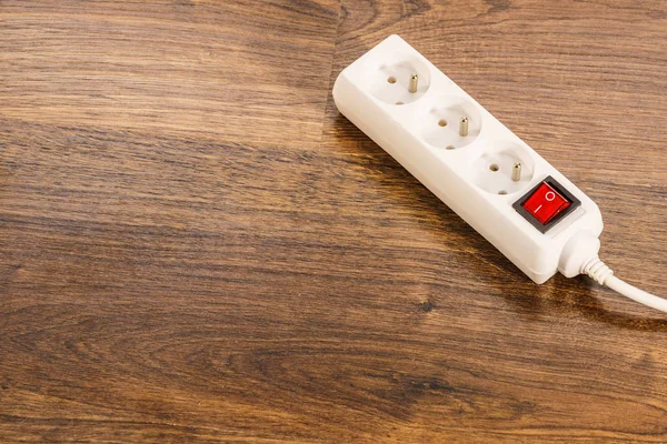 家里有电木质地板上带有红色开关的白色电源插头或延长线块 — 图库照片