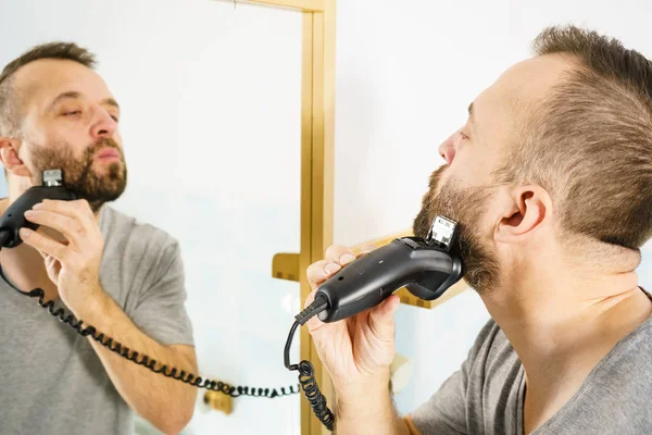 수염이 사람이 거울에 자신의 모습을 거울에 철면도기로 수염을 — 스톡 사진