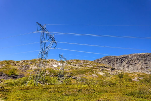 Power line spänning tower i bergen mot blå himmel — Stockfoto