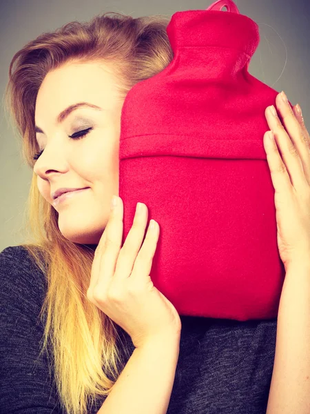 Mulher abraços garrafa de água quente na capa de lã vermelha — Fotografia de Stock