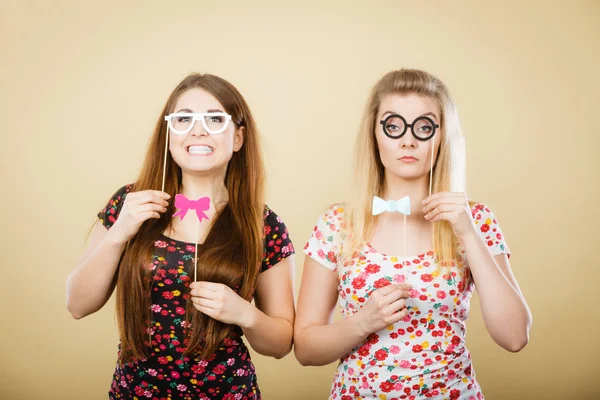 Deux femmes sérieuses tenant des accessoires de carnaval sur bâton — Photo