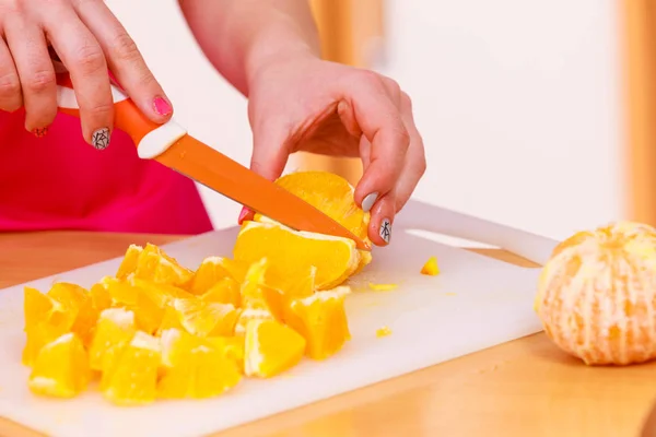 Kvinnan hemmafru i köket skär orange frukter — Stockfoto