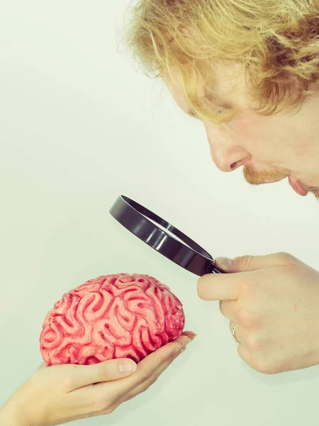 Hombre investigando cerebro humano usando lupa —  Fotos de Stock