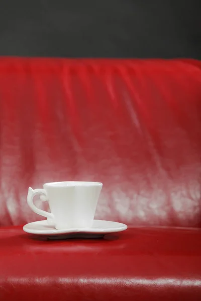 Pequeno chá branco de xícara de café no sofá vermelho — Fotografia de Stock