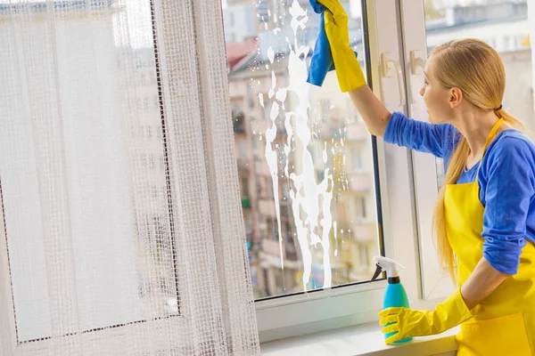 Woman cleaning window at home