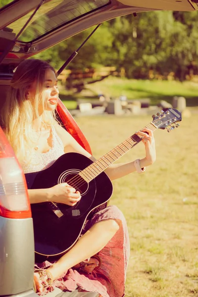 Hippie vrouw gitaarspelen in van auto — Stockfoto