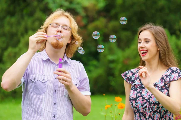 Pareja soplando burbujas de jabón, divirtiéndose — Foto de Stock