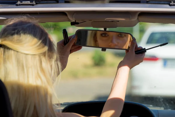 Mujer aplicando rímel en el coche — Foto de Stock