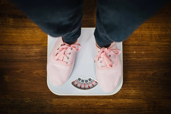 Женщина в розовых кроссовках на весе ванной — стоковое фото