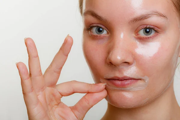 Frau entfernt Gesichtspeeling von Maske. — Stockfoto