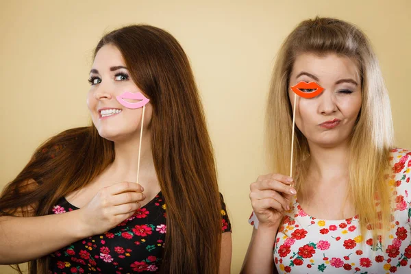 Twee gelukkige vrouwen houden van valse lippen op stick — Stockfoto