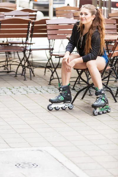 Ung kvinna sitter bär rullskridskor — Stockfoto