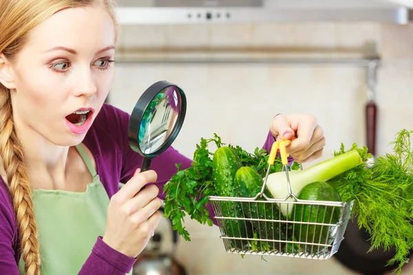 Donna guardando attraverso lente di ingrandimento a cesto di verdure — Foto Stock