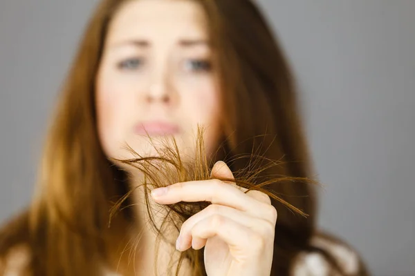 Mujer preocupada mirando sus puntas de cabello seco — Foto de Stock