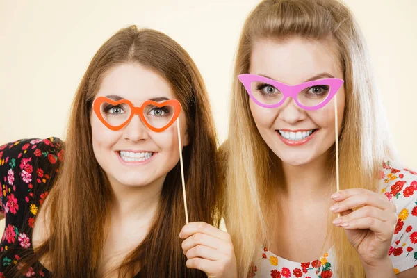 Twee gelukkige vrouwen houden van nep brillen op stick — Stockfoto