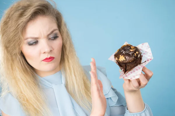 Skeptical woman holding chocolate cupcake muffin — Stock Photo, Image