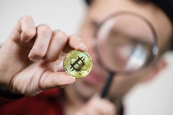 Man looking at bitcoin through magnifying glass — Stock Photo, Image