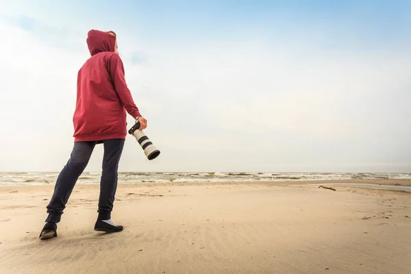 Woman walking on beach with camera — Stock Photo, Image