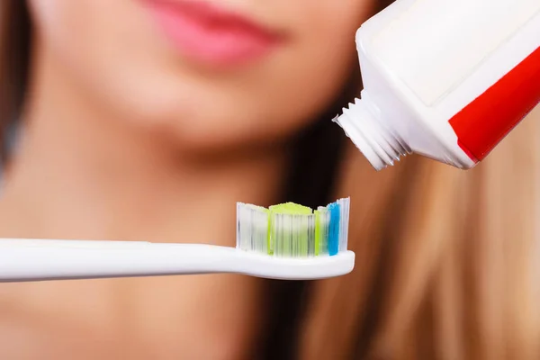 Mulher aplicando pasta de dentes em sua escova de dentes — Fotografia de Stock